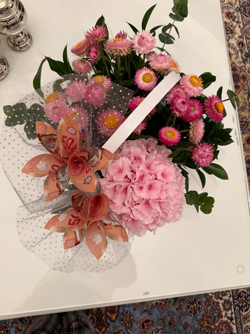 Pink hydrangea and bright pink flowers with greenery, folded banknote blooms and sheer dotted wrapping.